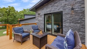 Une terrasse dotée de meubles en osier, d’un foyer extérieur et d’un mur en pierre.
