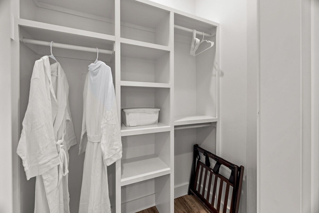 A white closet with shelves, a hanging rod, and a wooden crib.