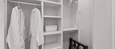 A white closet with shelves, a hanging rod, and a wooden crib.