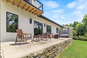 A modern house with a covered patio, outdoor seating, and a stone retaining wall.