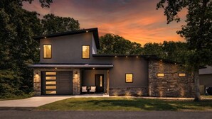 Una casa moderna de dos pisos con garaje, fachada de piedra y césped cuidado.
