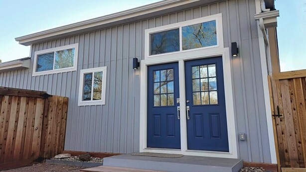 A two-story building with a blue front door, two windows, and a wooden fence. - Mountain Views, Peaceful Backyard, King Bed, Dog Friendly (Colorado Springs)