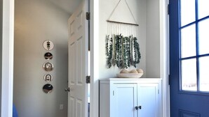 A hallway with a white door, a blue door, and a wall-mounted plant. - Mountain Views, Peaceful Backyard, King Bed, Dog Friendly (Colorado Springs)