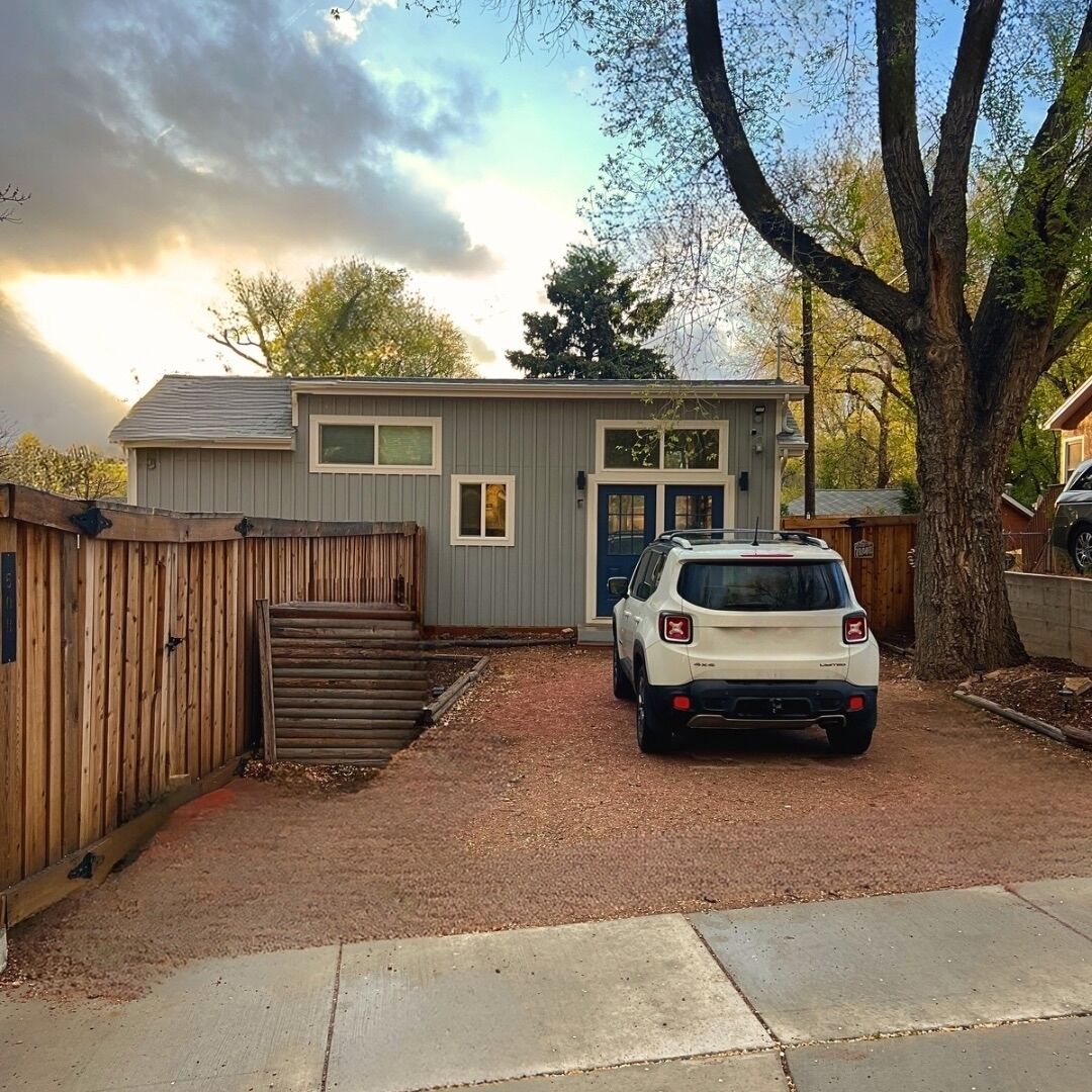 Ein kleines, eingeschossiges Haus mit einer Haustür, einer Garage und einer Auffahrt.