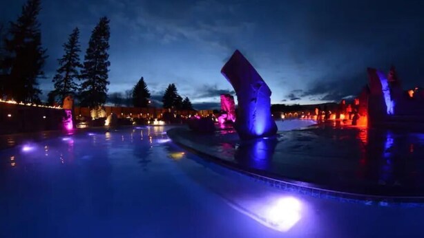 A nighttime swimming pool with illuminated structures and trees in the background. - Sky Lodge House - 3BR+BBQ - 5 min to BZN Airport (Belgrade)