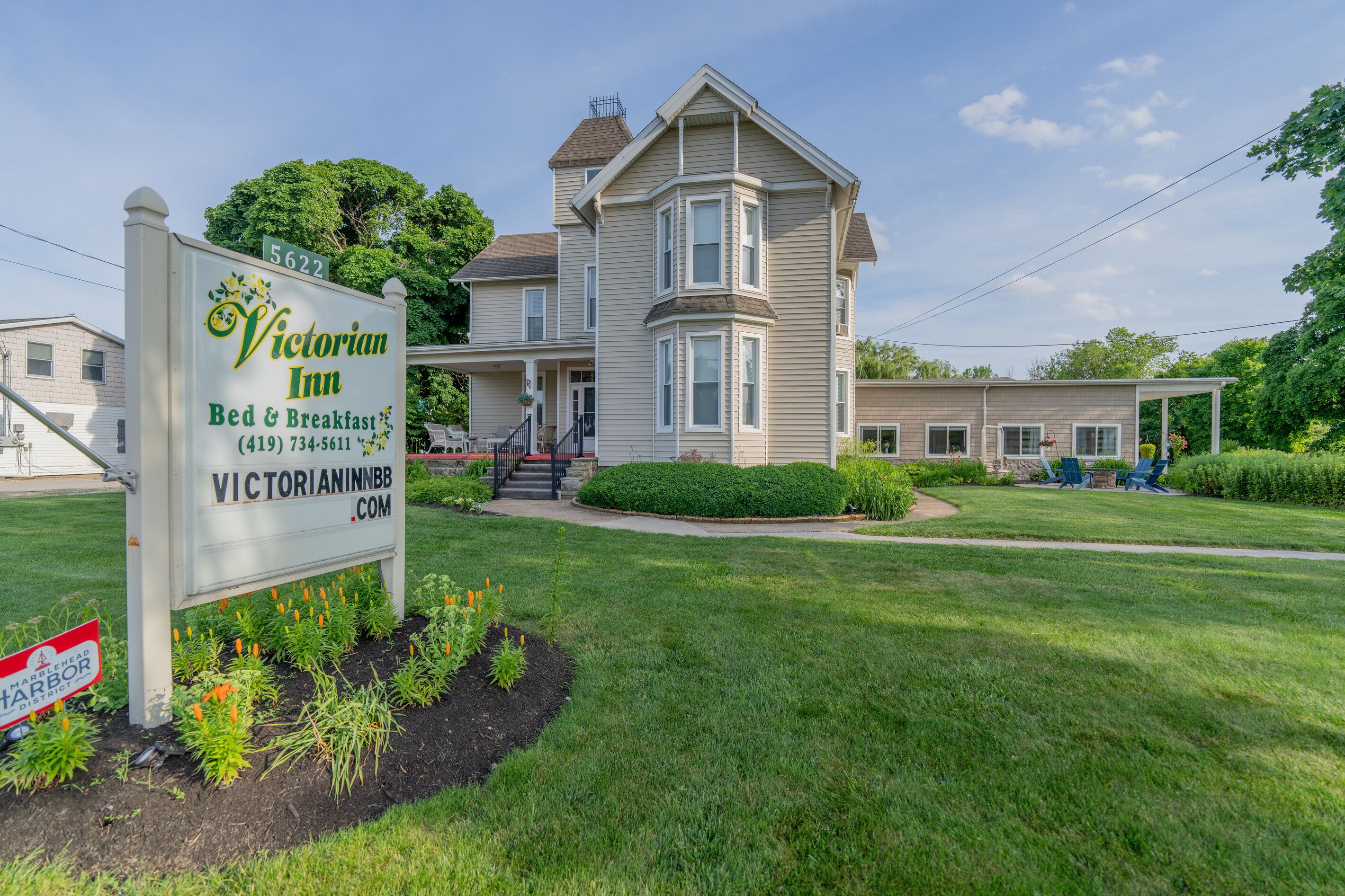 A Victorian Inn with a large two-story building, a signboard, and a well-maintained lawn.