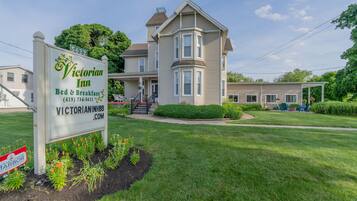 A Victorian Inn with a large two-story building, a signboard, and a well-maintained lawn.