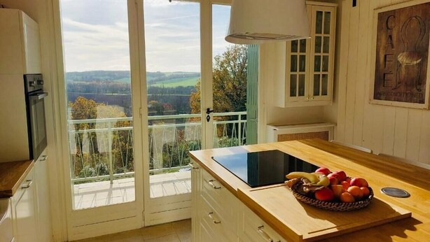 Eine Küche mit einem großen Fenster, einer Holzausziehtheke und einer Fruchtschüssel.