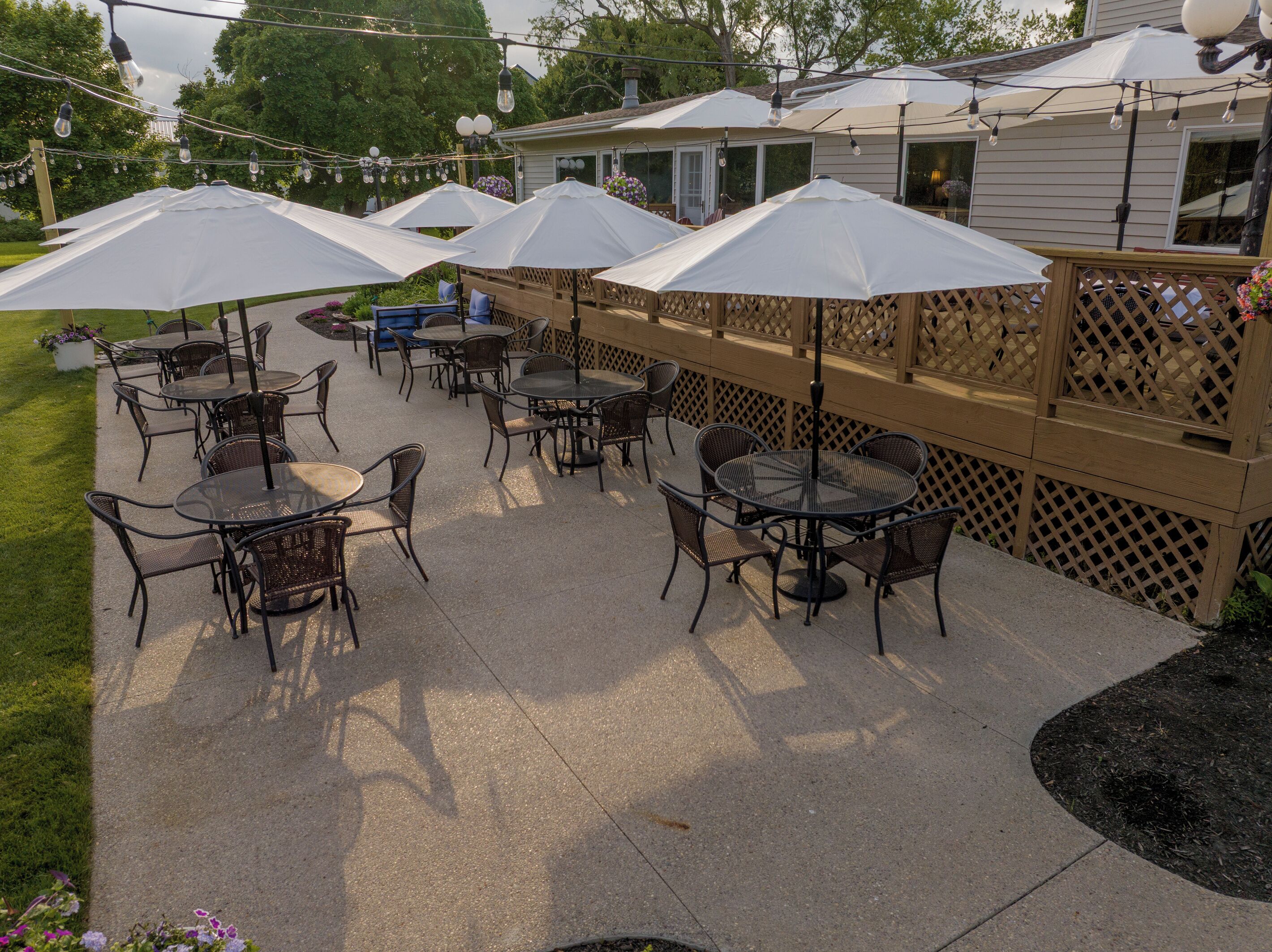 An outdoor patio with tables and chairs, umbrellas, and string lights.