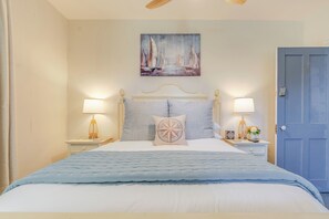 A bedroom with a bed, two bedside tables, a nightstand, a door, and a painting on the wall.