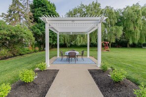 A garden with a white pergola, a table with chairs, and a swing set. - Relaxing Couples Retreat Near Lake Erie (Lakeside-Marblehead)
