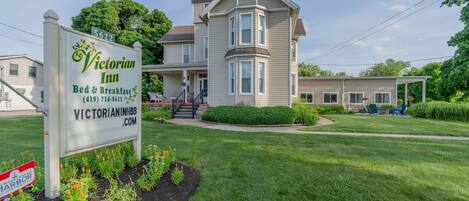 A Victorian Inn with a large two-story building, a signboard, and a well-maintained lawn.