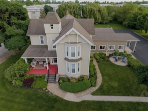 A two-story house with a covered patio, a landscaped yard, and a driveway. - Relaxing Couples Retreat Near Lake Erie (Lakeside-Marblehead)