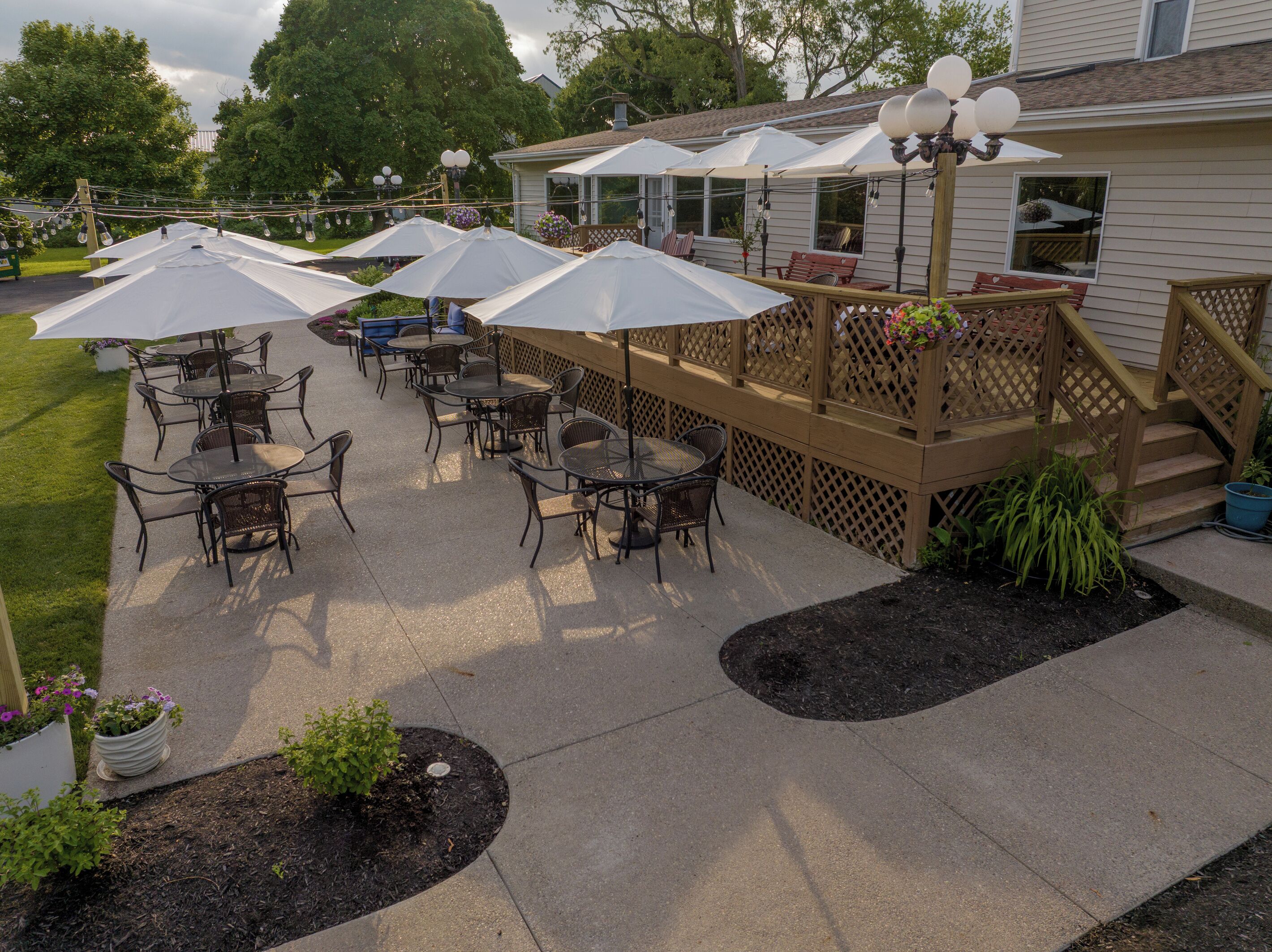 An outdoor patio area with tables and chairs, umbrellas, and a wooden deck.