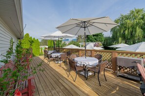 An outdoor patio with tables and chairs, umbrellas, and a wooden deck. - Relaxing Couples Retreat Near Lake Erie (Lakeside-Marblehead)