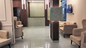 Eine moderne Lobby mit bequemen Sitzgelegenheiten, einer Marmorsäule und einem Flachbildfernseher an der Wand.