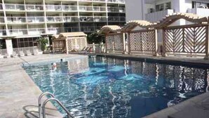 Una piscina con cubierta de madera y un edificio al fondo.