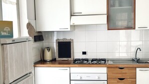 A modern kitchen with white cabinets, a wooden countertop, a gas stove, a kettle, and a sink. - N289 - Numana, two-room apartment with garden (Numana)