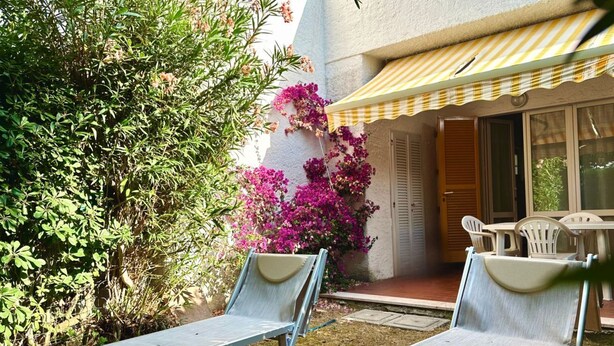 A patio with two lounge chairs, a yellow-striped awning, and a door leading to a covered area. - N289 - Numana, two-room apartment with garden (Numana)