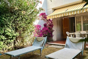 A patio with two lounge chairs, a yellow-striped awning, and a door leading to a covered area. - N289 - Numana, two-room apartment with garden (Numana)