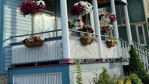 Una casa de dos pisos con un balcón decorado con macetas colgantes de flores.