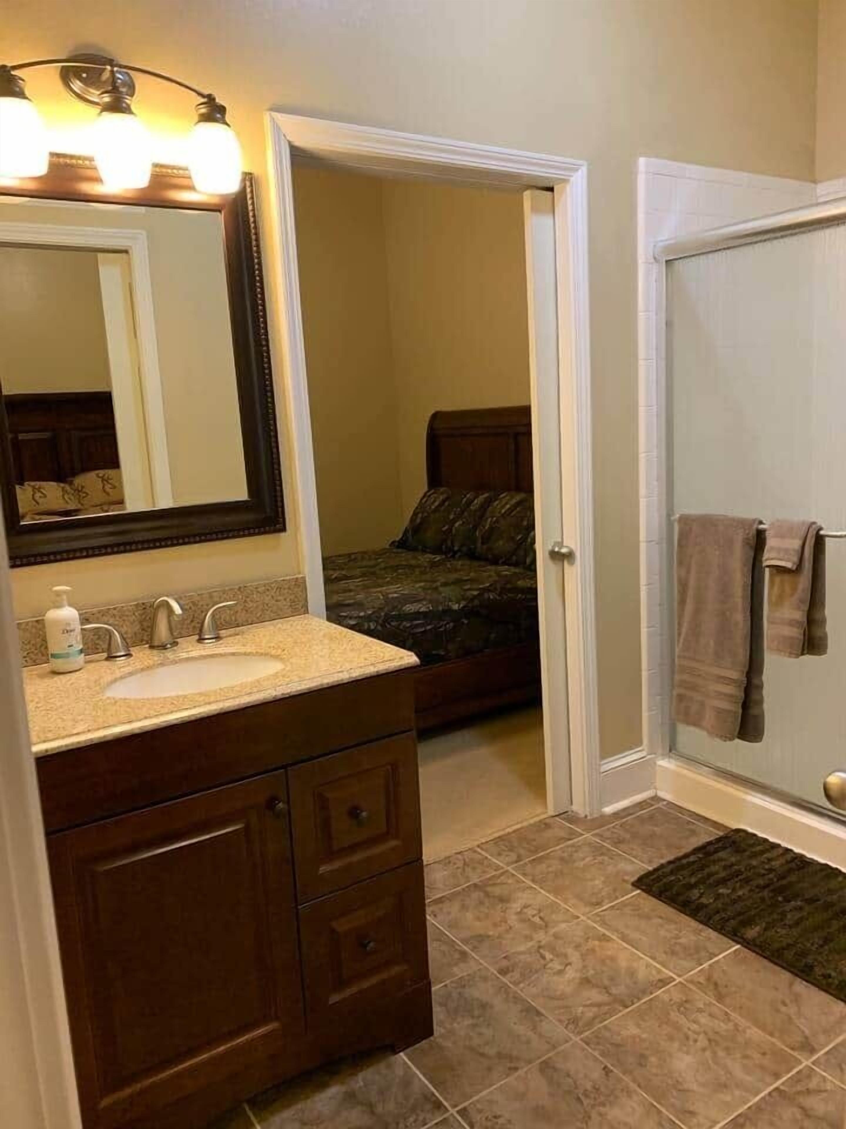 A bathroom with a sink, mirror, and shower.