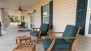 A covered porch with wooden furniture, including chairs and a table. - Grandview Acres Lodge (DeWitt)