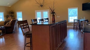 A spacious kitchen with a high ceiling, wooden cabinets, and a central island. - Grandview Acres Lodge (DeWitt)
