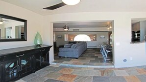 Un amplio salón con sofá, una barra de comedor y zona de cocina.
