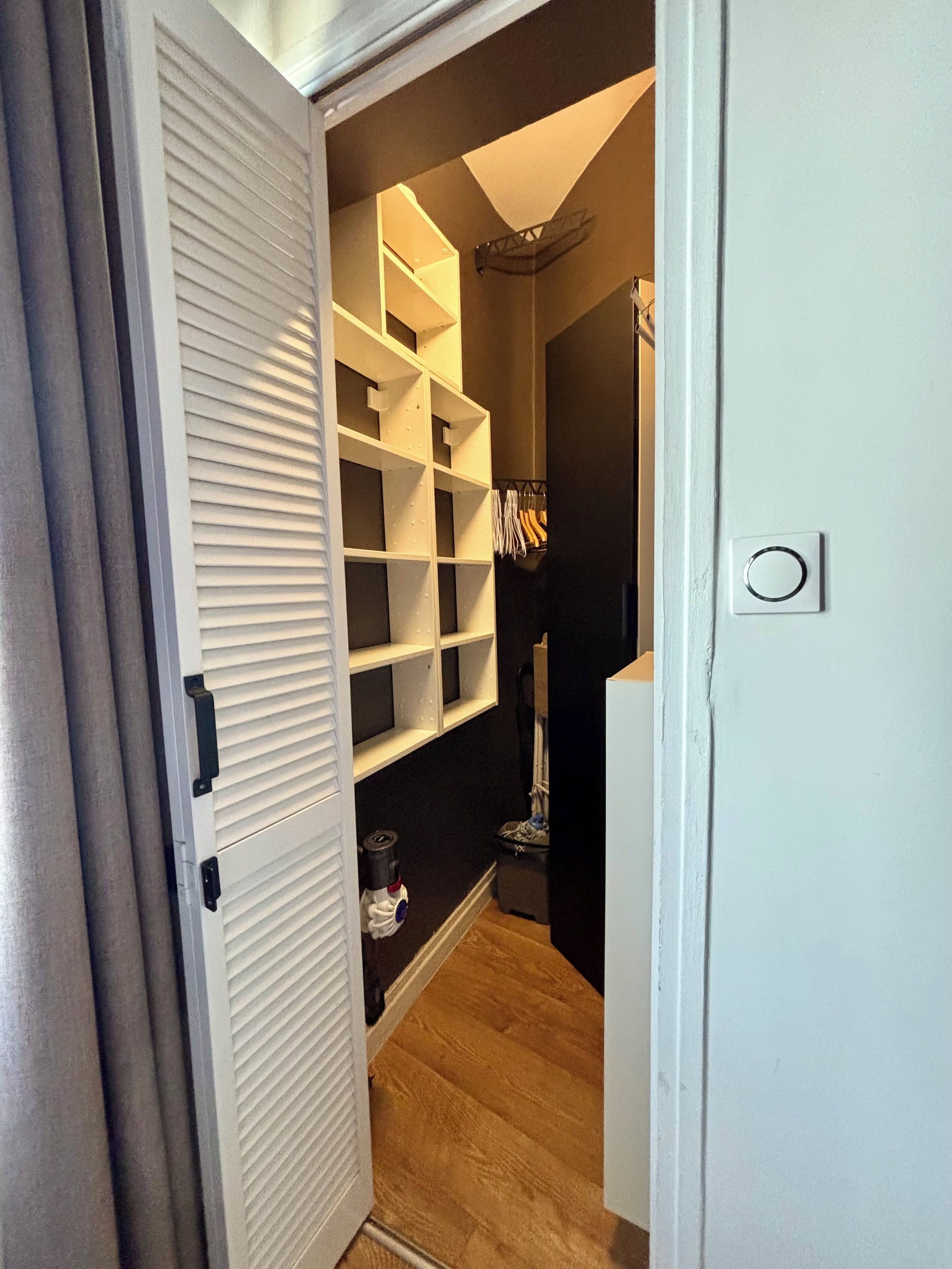 A hallway with a white closet, a vacuum cleaner, and a broom.