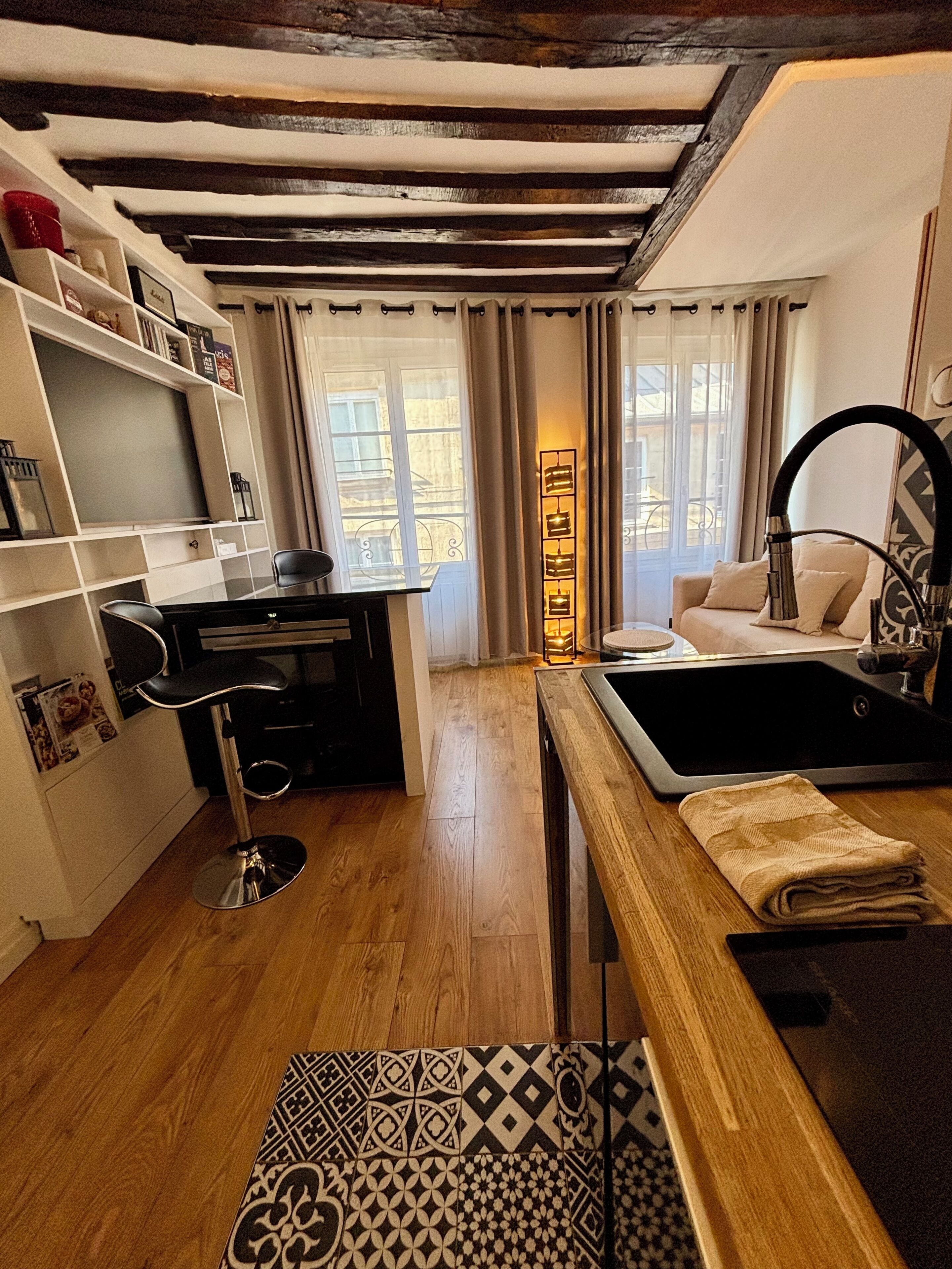 A compact living space with a kitchenette, a dining area, and a seating area with a sofa and a chair.