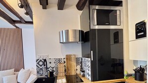 A modern kitchen with a black refrigerator, wooden cabinets, and patterned backsplash. - Charming Apartment in Center Paris (Paris)
