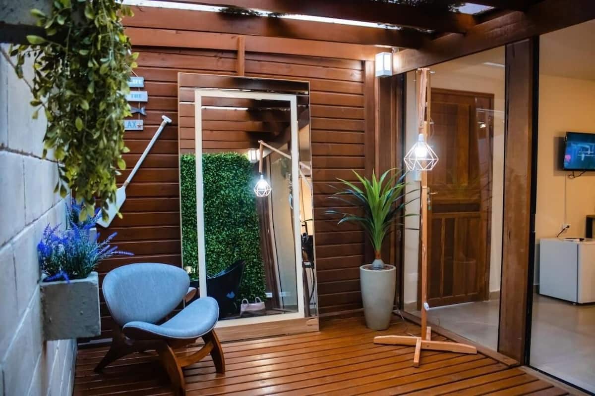 A wooden deck with a chair, a potted plant, and a hanging plant.