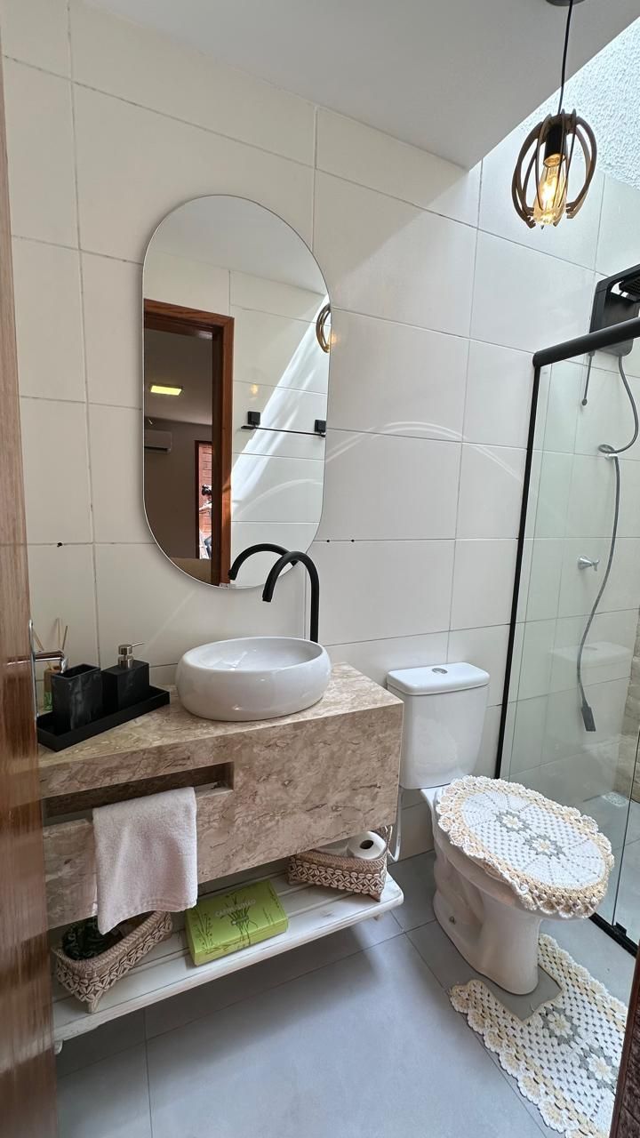 A modern bathroom with a round mirror, a sink, a toilet, and a glass-enclosed shower.
