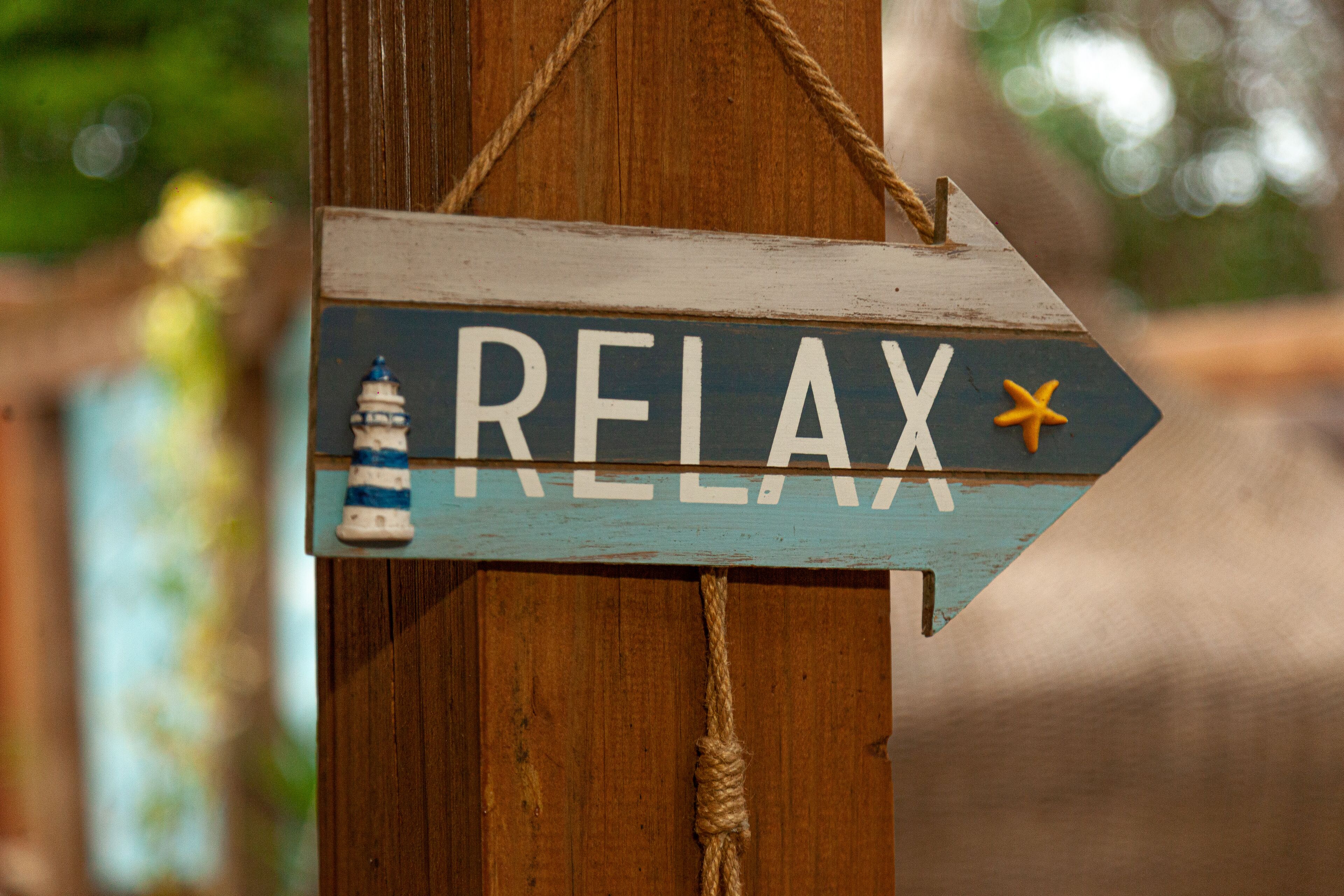 Une enseigne en bois sur laquelle est inscrit le mot « RELAX » et qui est décorée d’un phare.