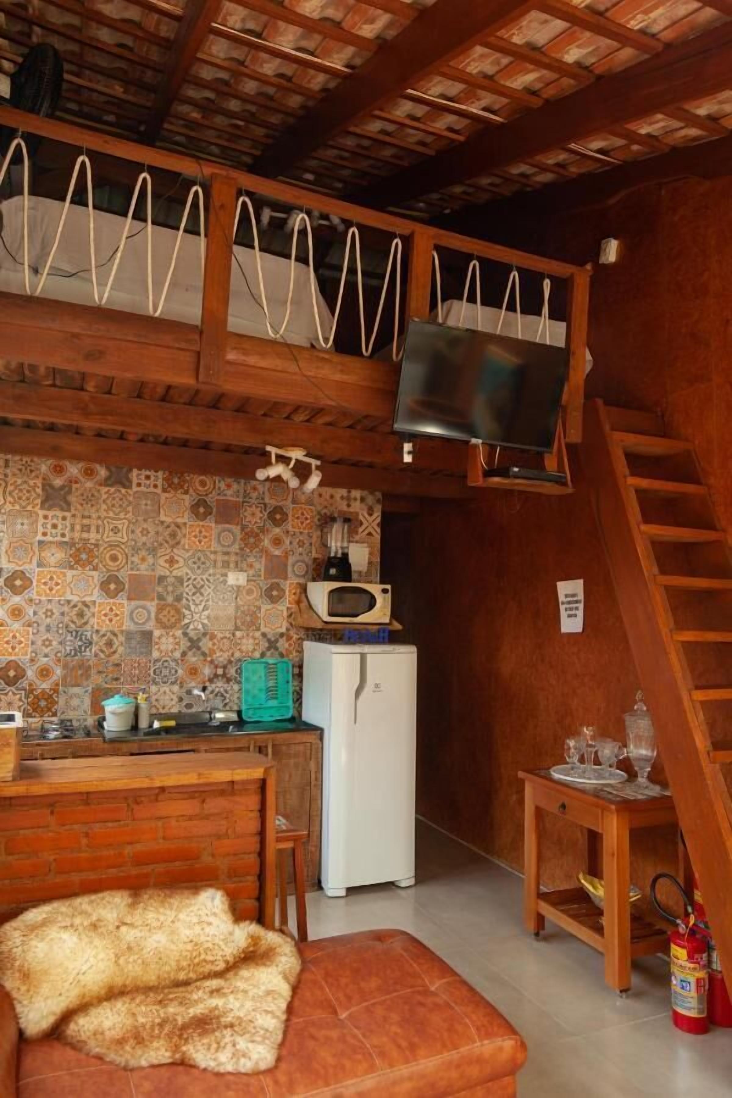 A compact kitchen with a tiled backsplash, a microwave, a refrigerator, and a wooden counter.