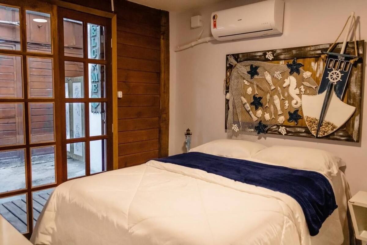 A bedroom with a bed, a wooden door, and a wall-mounted air conditioner.
