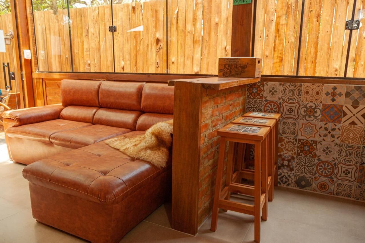 Un divano in pelle marrone con una coperta in pelliccia, un bancone bar in legno e una parete rivestita di piastrelle decorate.