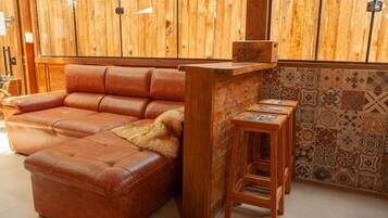 Un divano in pelle marrone con una coperta in pelliccia, un bancone bar in legno e una parete rivestita di piastrelle decorate.