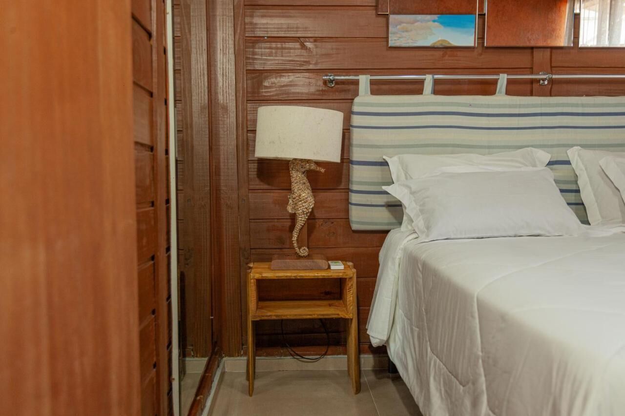 Una stanza con rivestimenti in legno, un letto, una testiera a righe, un comodino in legno con una lampada e una piccola mensola.