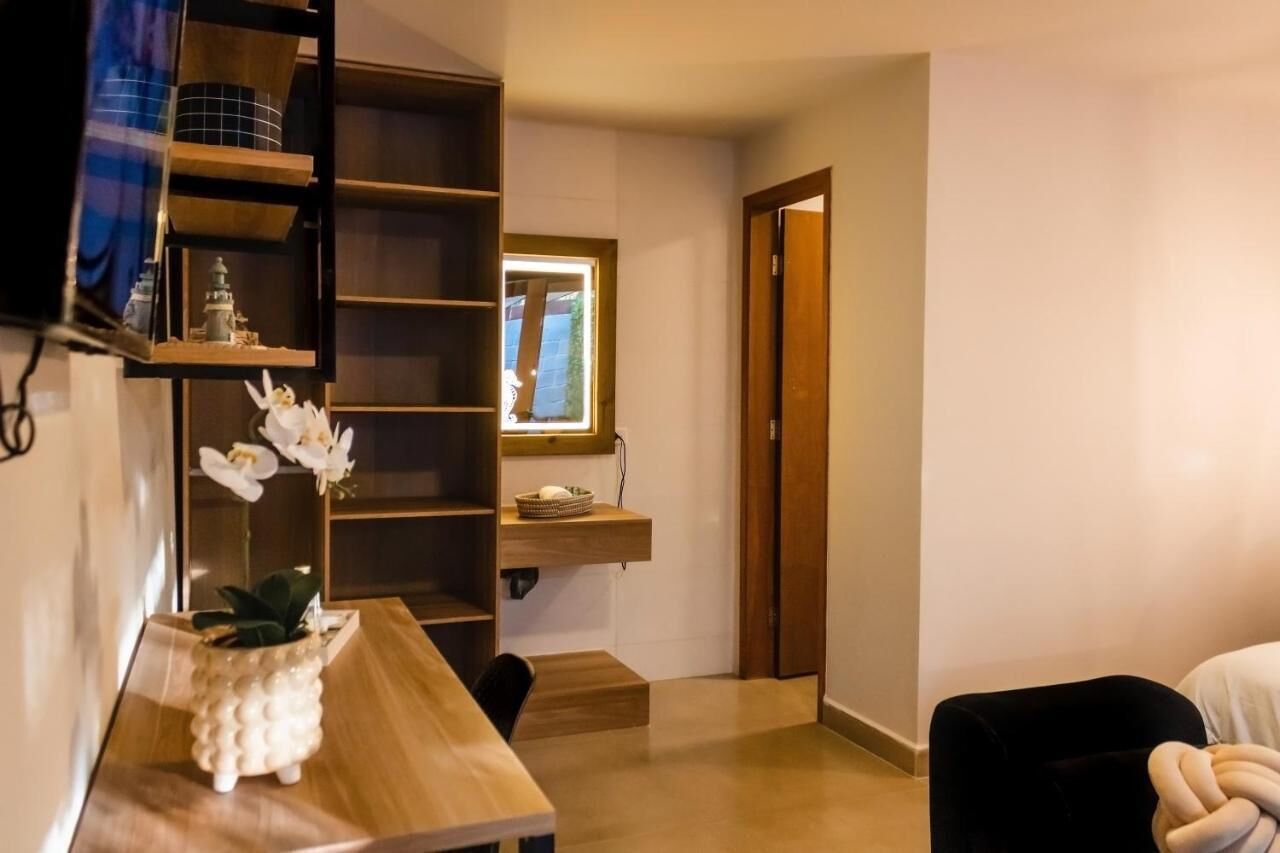 A room with a wooden desk, a chair, a bookshelf, and a small window.