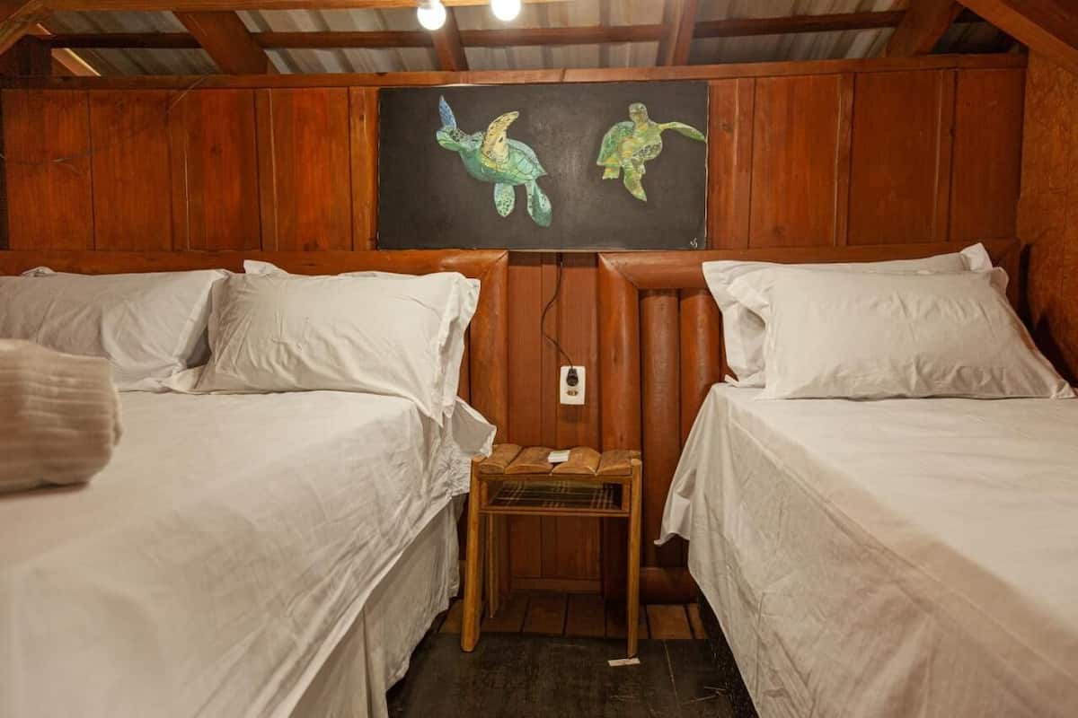 A room with two beds, wooden walls, and a painting of turtles on the wall.