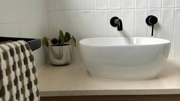 A bathroom with a white sink, black faucet, and a round mirror above it.