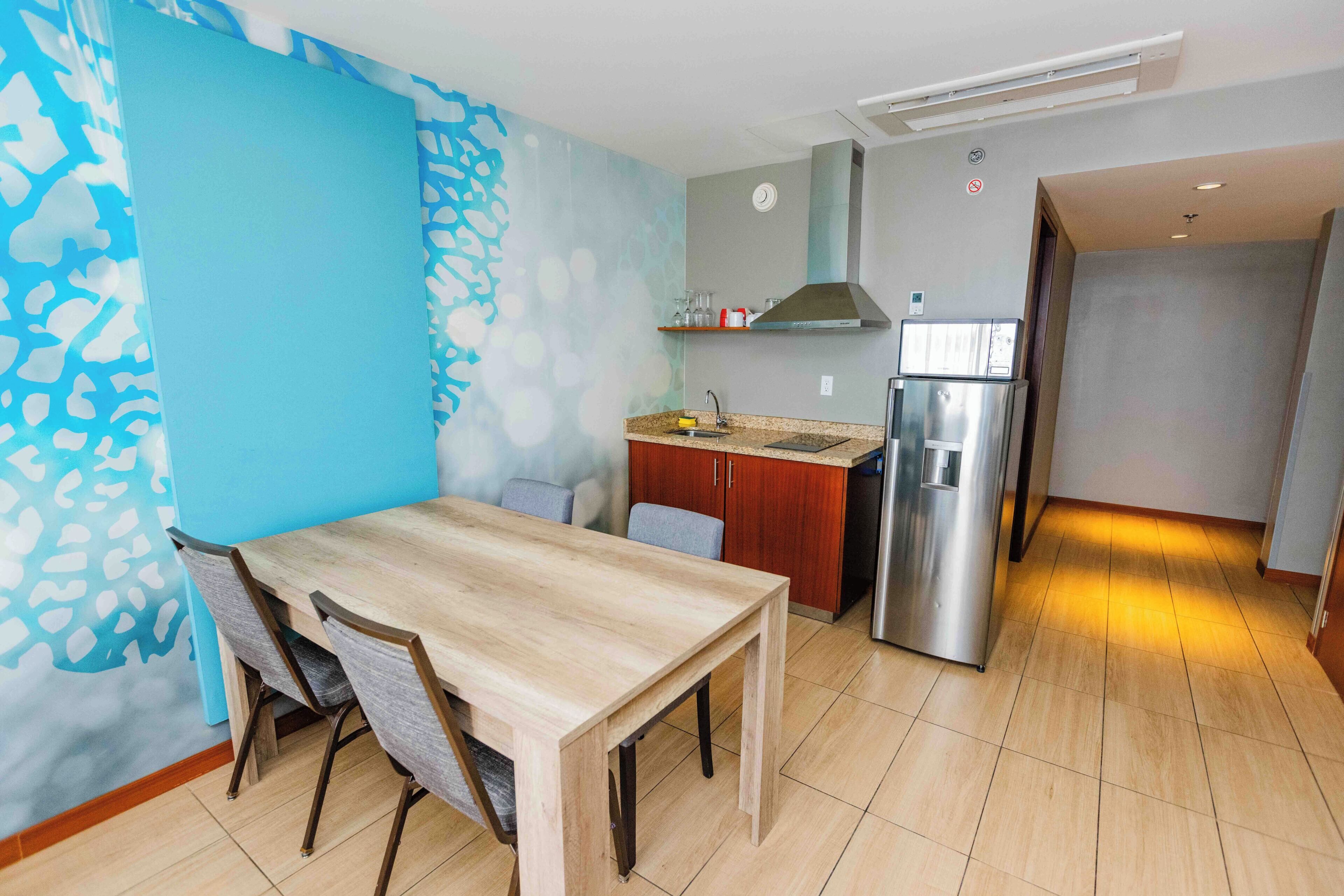 Een moderne keuken met een eettafel, stoelen, een koelkast en een magnetron.