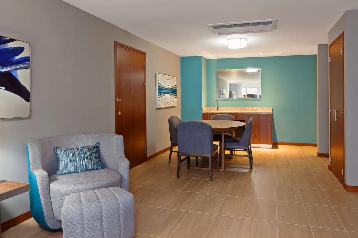 Una habitación de hotel moderna con comedor, un ventanal grande y una kitchenette.