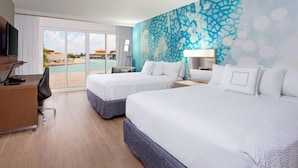 Quarto de hotel com duas camas, uma mesa, uma cadeira, televisão e uma janela grande com vista para a piscina e edifícios.