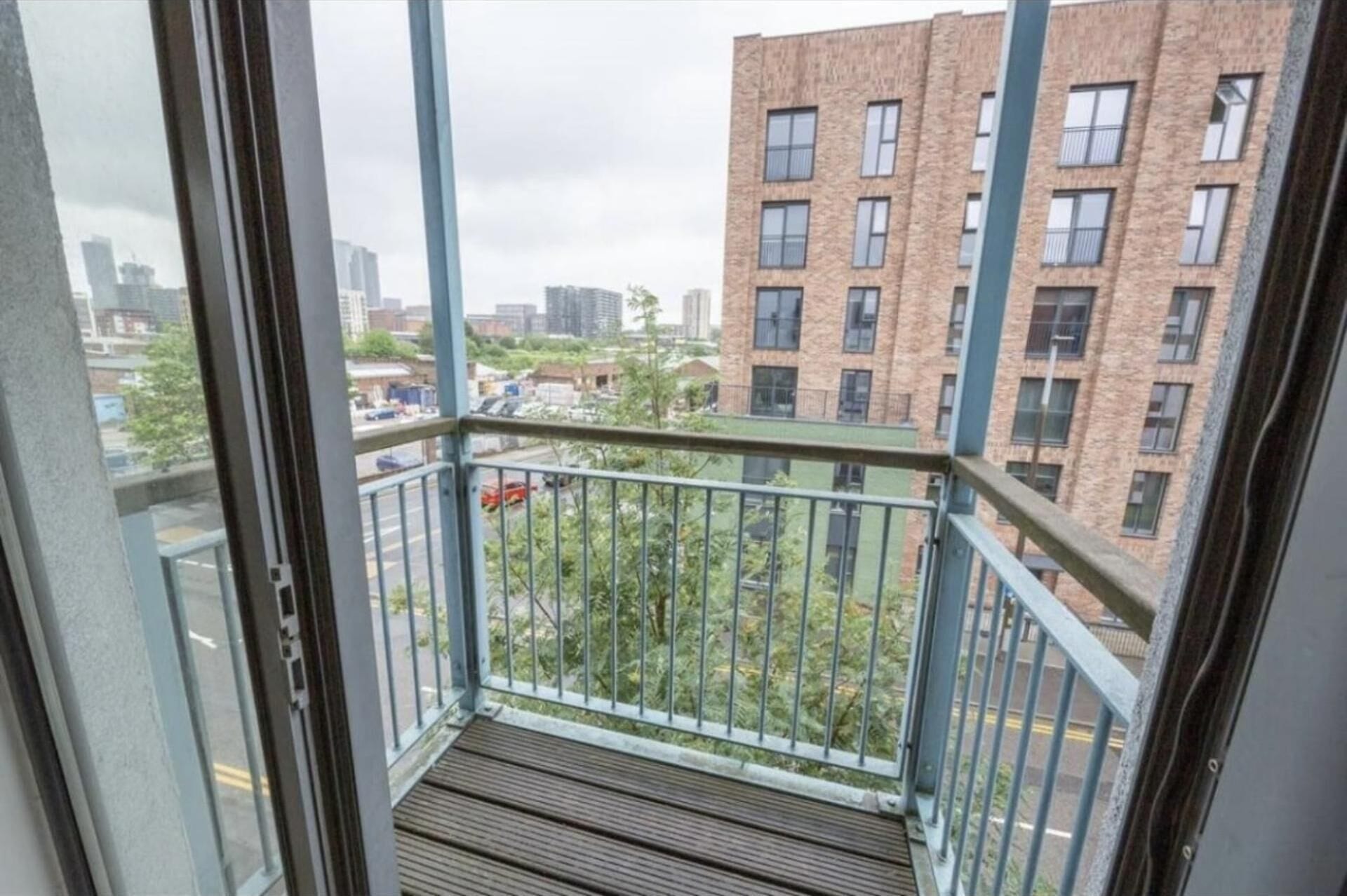 En balkon med udsigt til en murstensbygning og en gade.