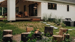 Ett hus med en inglasad veranda, utomhusmöbler och en eldstad.