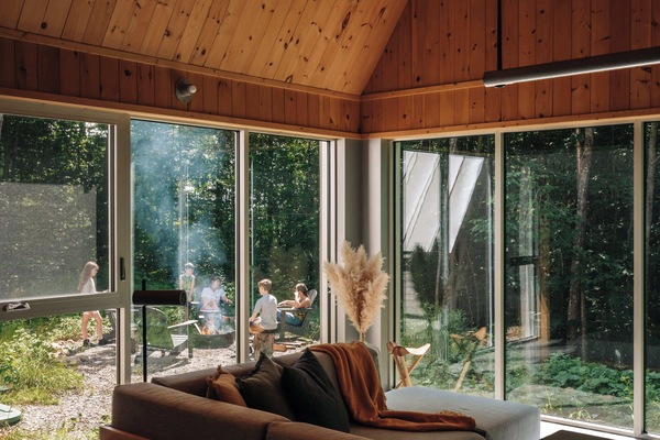 Gather with family, forest views framing outdoor fireside tales.