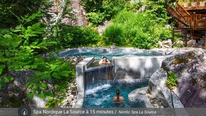 Zona de aguas termales con una pasarela de madera y una cascada.